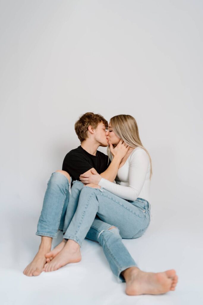 sitting couples pose with girls legs around mans and kissing while he holds her cheek