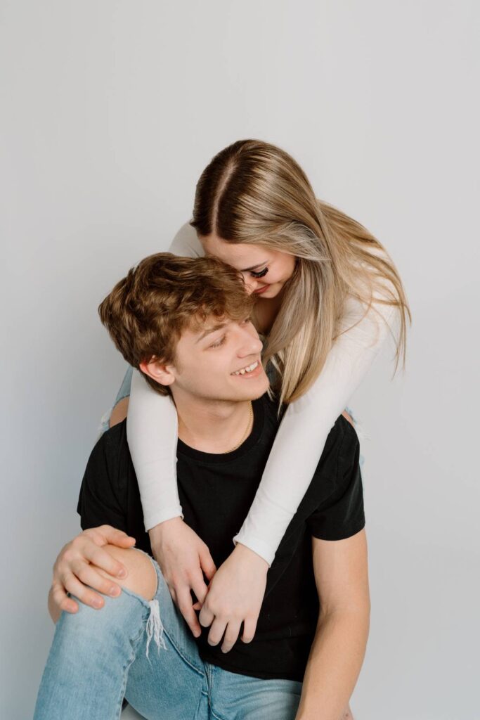 girl sitting behind boy during pictures head leaning into his while he sits on the ground beneath her