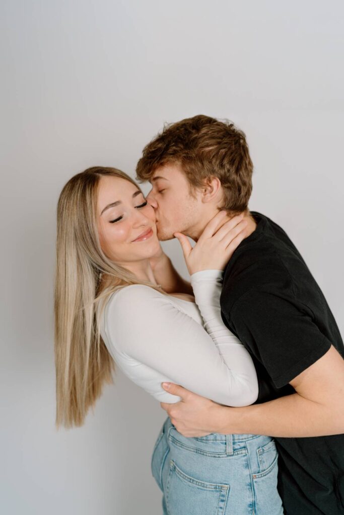 still pose of man kissing girl on cheek girls eyes are closed and smiling