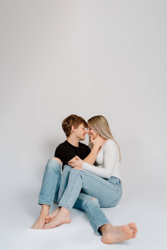 Couples photoshoot where the women has legs over top of man and they are about to kiss