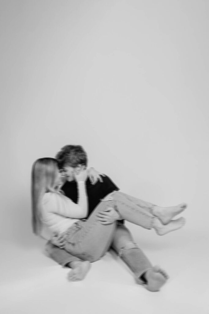 Movement image of couple during photoshoot of man rocking his girl back and fourth