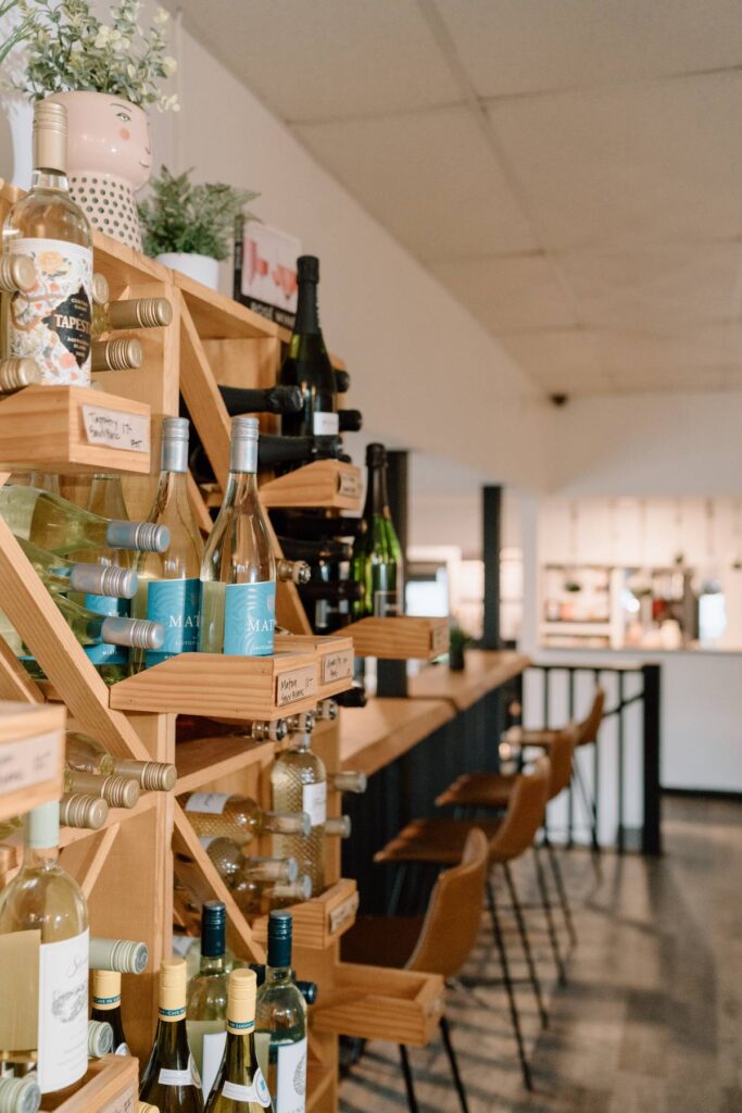 interior of a coffee shop alongside a wall of seating and a wine shelf