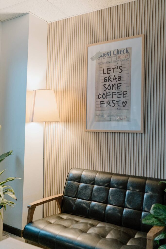 picture of interior of coffee shop with black couch, coffee sign and a lamp