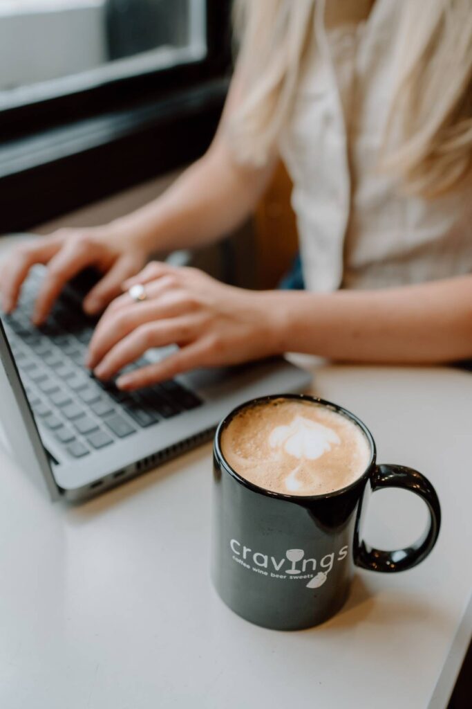 person working at a coffee shop with a photography taking a detail shot of the cup with their logo