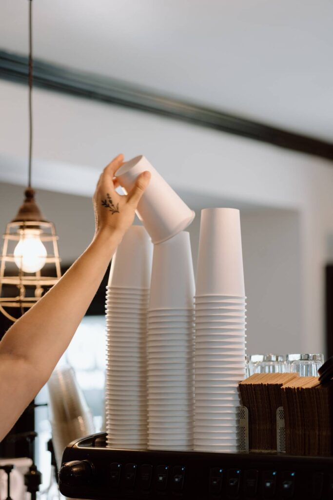 barista reaching for a cup while making a drink, showcasing coffee shop 