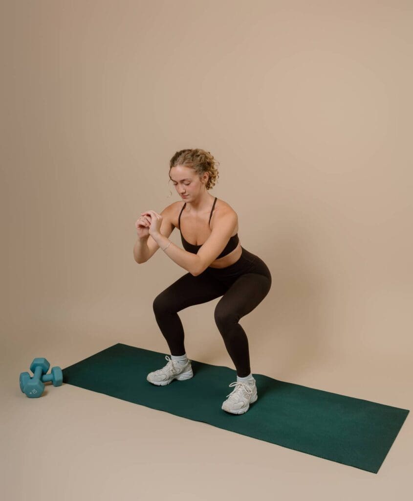 Client demonstrating a squat on a yoga mat on top of photography backdrop