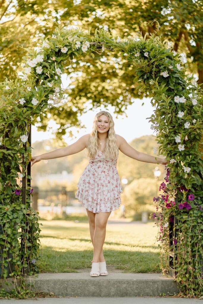 Kalea laughing and twirling in a flower-filled garden during her senior session.